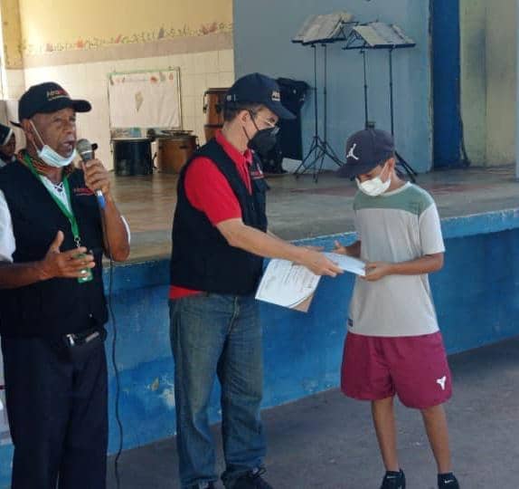 Un adolescentes recibe su diploma de manos de Reinaldo Bolívar
